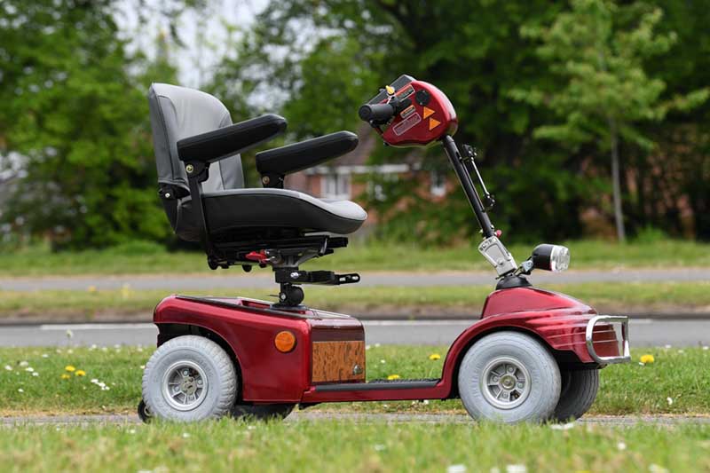 A red mobility scooter parked in a park