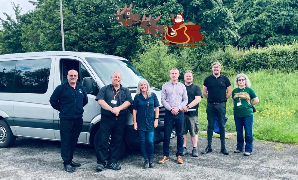 The Herts Ability team standing in front of a grey minibus.