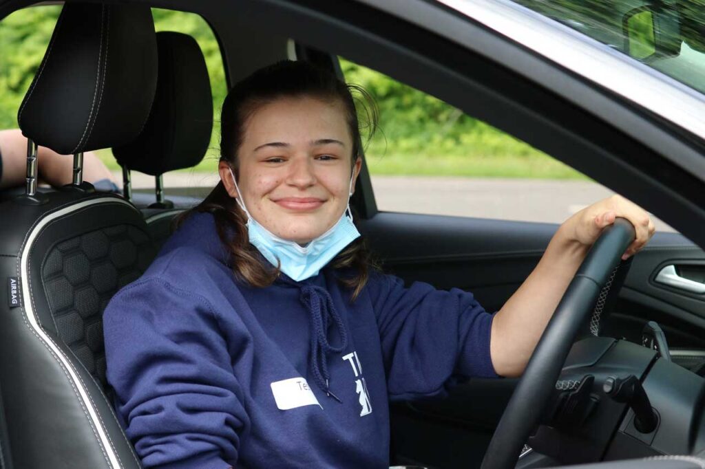 A young woman facing the camera while sat in her adapted car.