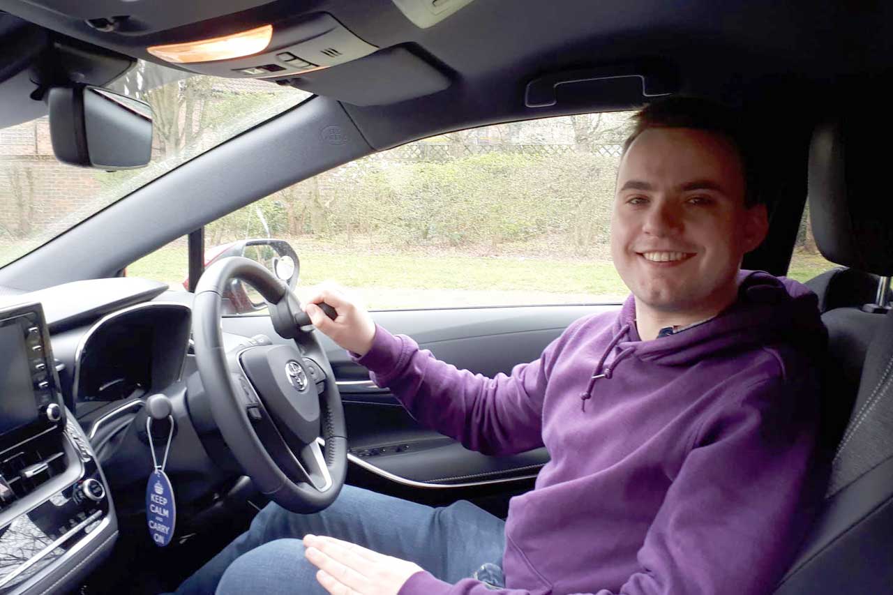 A man sat in the driving position of his adapted car.