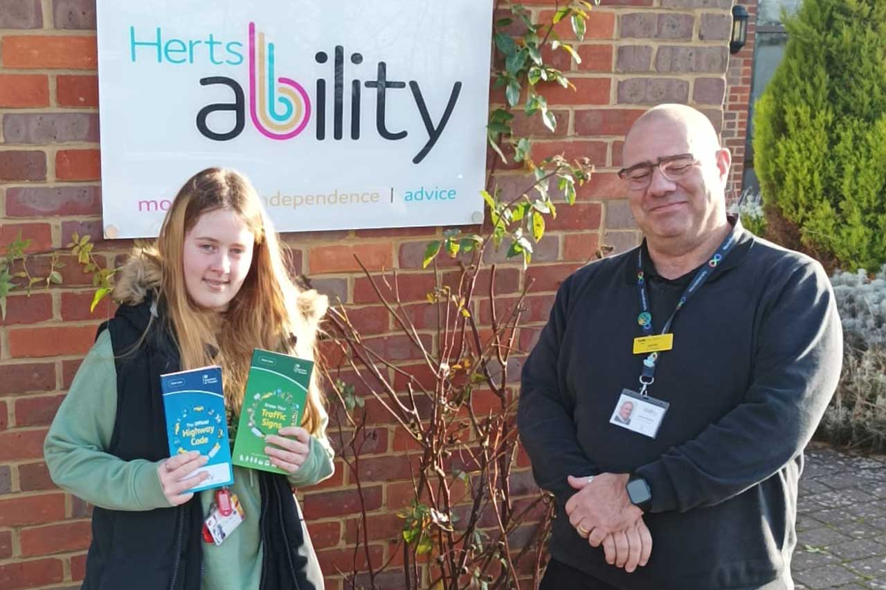 A young woman holding her theory test certificate with the driving assessor.